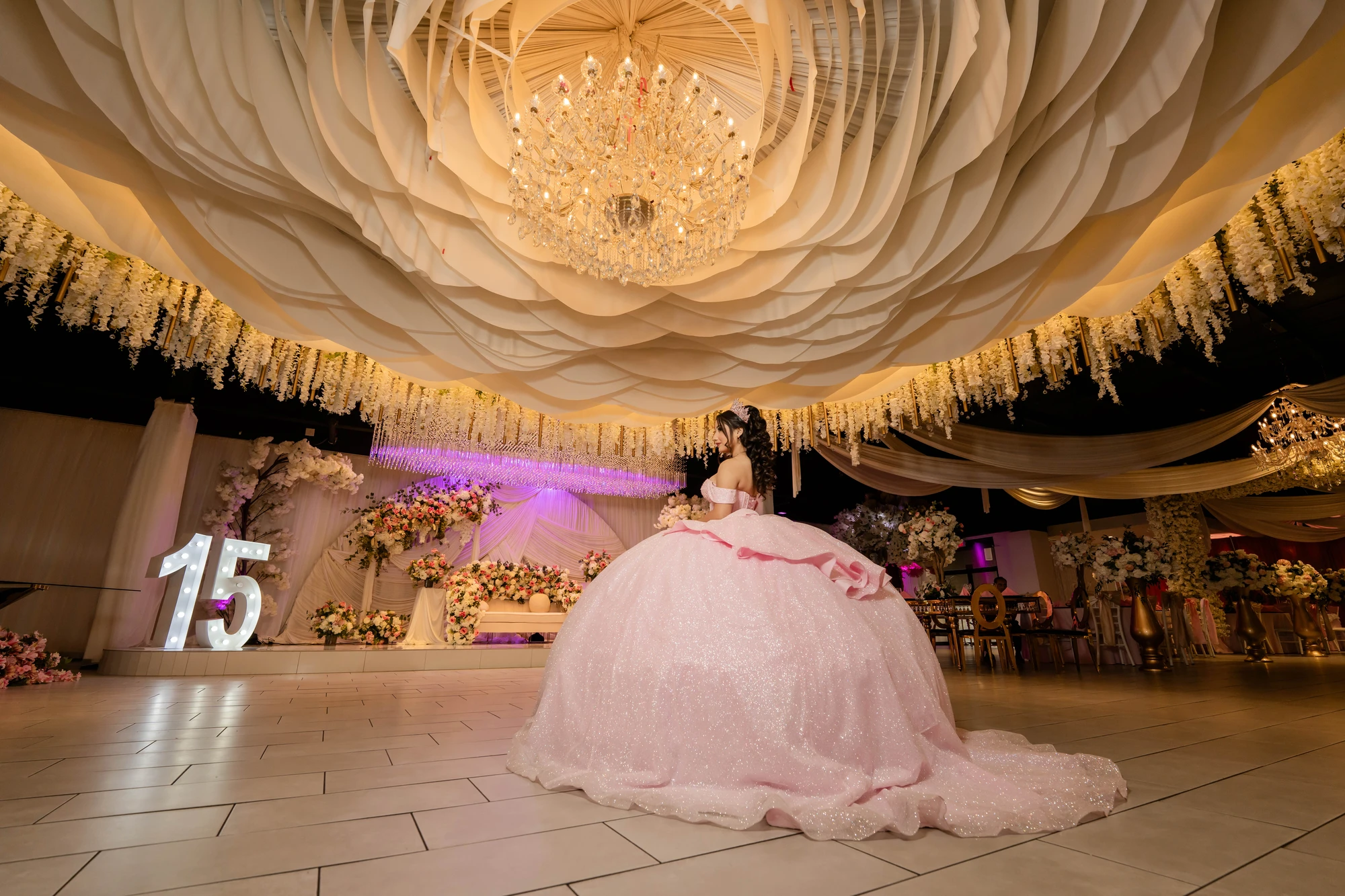 Quinceañera celebration with pink decor and chandelier at La Bella Luna Venue